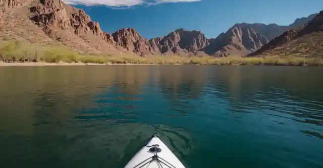 A person kayaking on the serene waters of Saguaro Lake with majestic mountains in background.
