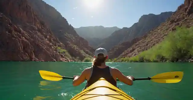 A person kayaking on the placid waters of Canyon Lake in sunny Arizona with lush green mountains as a backdrop.