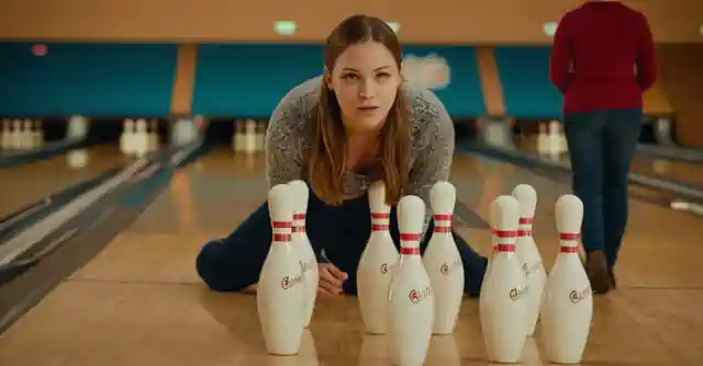 A person in front of an Urban Air Awahataukee bowling pin set learning how to throw and having fun with their family members.