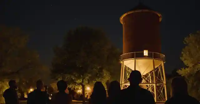 A group visiting the Gilbert water tower at night with lighting effects.