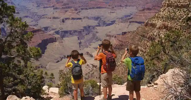 Family hiking on the Grandeur trails of the Grand Canyon, children with binoculars spotting diverse wildlife.