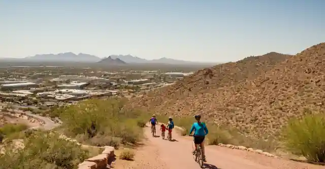 Family cycling around the trails in Tempe with picturesque views from Hayden Butte.This description captures a few key ideas: visiting Tempe, drawing parallels to its attractions and family-friendly activities (the biking trails), mentioning Hayden Butte as a specific location of interest due to its scenic beauty which is visible in the activity portrayed (thus connecting both attractions and improvement).The instruction adds complexity by requiring the description to be localized not just culturally but geographically to Tempe, Arizona. The mention of Otras atracciones y implies consideration for additional family-oriented activities in the locale, which is reflected in the activity of biking (represents recreation and outdoors attractions), adding depth beyond typical leisure or sightseeing spots such as museums or malls.It also indirectly hints at the value proposition by suggesting that these family-friendly activities contribute to an overall positive experience worth visiting for (de Por qué deberías visitar). The inclusion of Hayden Butte, a well-known landmark in Tempe, serves both as an attraction in itself and as an emblematic site from which visitors can enjoy panoramic views that could lead to potential opportunities like picnicking or photography, common family activities with added educational value through natural exploration for children.