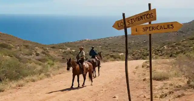 A signpost in Spanish that says Los eventos especiales se llevan a cabo hoy with the image of horse-riding and hiking silhouettes as background.