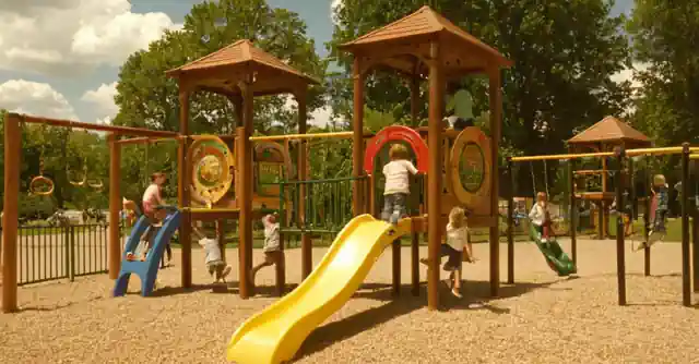 Children playing on modern play equipment in Johnnys Playground with promotional signs.