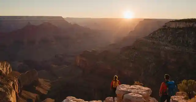 Sunsets over the Grand Canyon with hikers in front.
