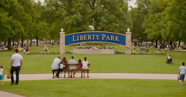 Families enjoying different activities in the park with Liberty Park sign as backdrop.