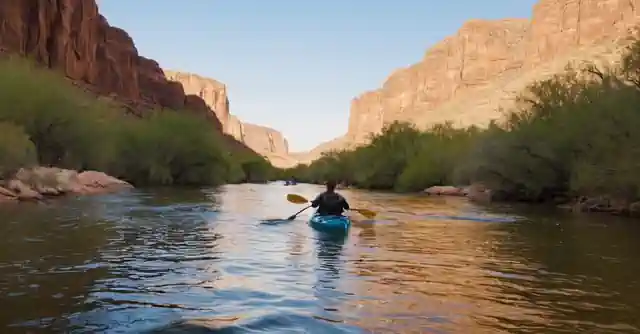 Kayaking on an Arizona river, surrounded by the desert landscape, under the blue sky.