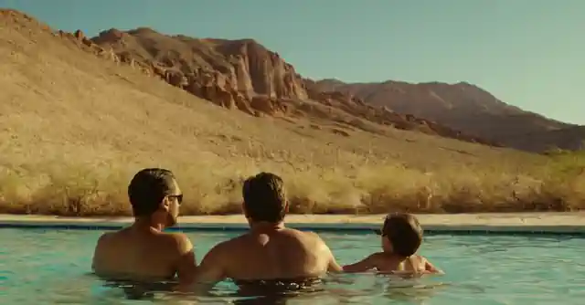 Família disfrutando la natación bajo el suave sol del desierto. (Family enjoying swimming under the mild desert sun.)