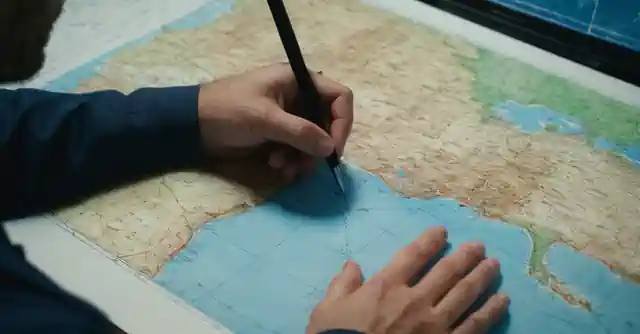 Person evaluating geographic maps and climate charts with a blueprint sketch.