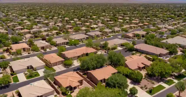 Person reviewing pros and cons list about living in Surprise, Arizona on screen.