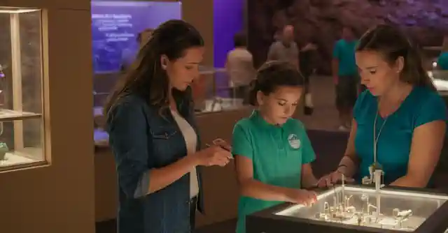 Parents alongside their child exploring a science exhibit at Camp STEM in Phoenix.