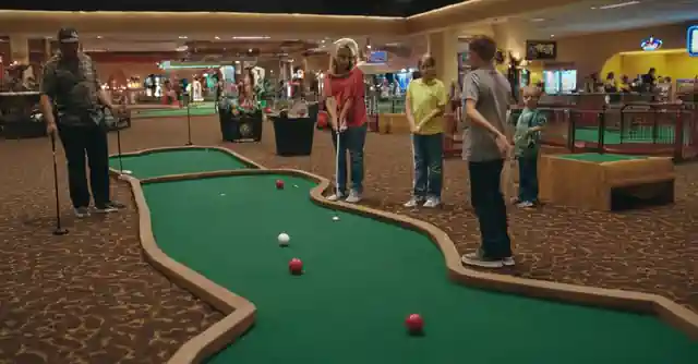Families playing miniature golf at an indoor arcade in Gilbert, Arizona.